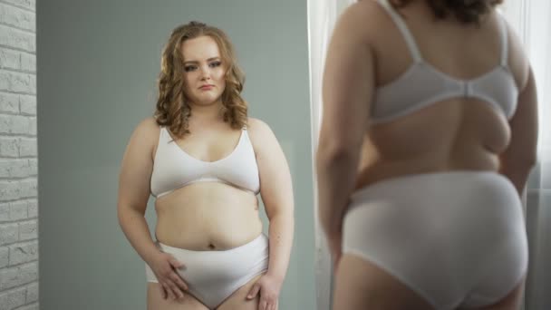 Obese lady in underwear looking at reflection in mirror, ashamed of her fat body — Stock Video