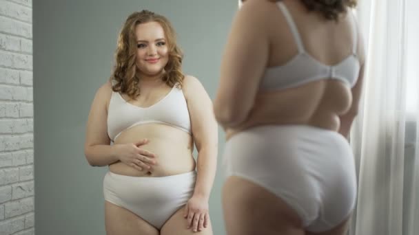 Szczęśliwa dziewczyna patrząc w lustro po liposukcji, radowanie się jej nowy wygląd — Wideo stockowe