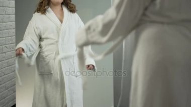 Şişman kadın bornoz ve ayna önce alarak duş bakarak iç çamaşırı