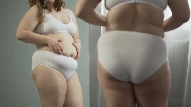 Молодая женщина, глядя на живот, хочет сбросить лишний вес, риск заболеваний — стоковое видео