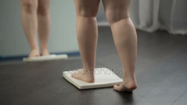 Толстая женщина получает на весах для контроля веса во время здорового питания, потеря веса — стоковое видео