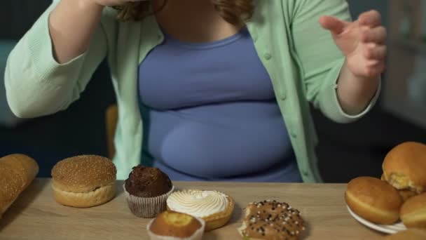 Mulher jovem corpulenta comendo pastelaria gananciosamente, comendo alimentos gordurosos insalubres — Vídeo de Stock