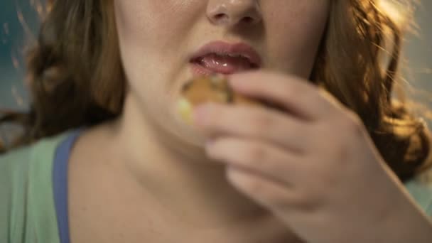 Mollige vrouw donut bijten en kauwen het overeten zoet gebak, gezicht close-up — Stockvideo