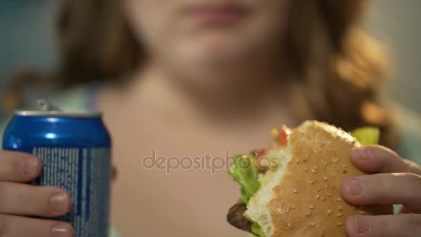 Ragazza mangiare hamburger grasso e bere soda zuccherata da lattina, mangiare troppo cibo spazzatura — Video Stock