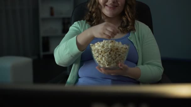 Overgewicht vrouwelijke nemen handvol popcorn en eten voor Tv thuis — Stockvideo