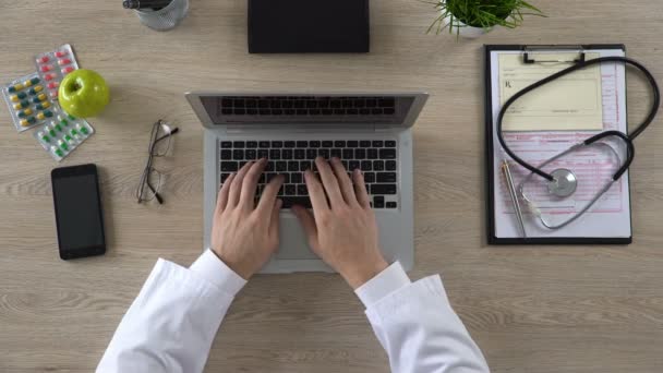 Medico che lavora su laptop, consulto paziente online, clinica moderna, vista dall'alto — Video Stock