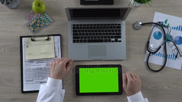 Медицинский работник проверяет информацию о здоровье на планшете с зеленым экраном, вид сверху — стоковое видео
