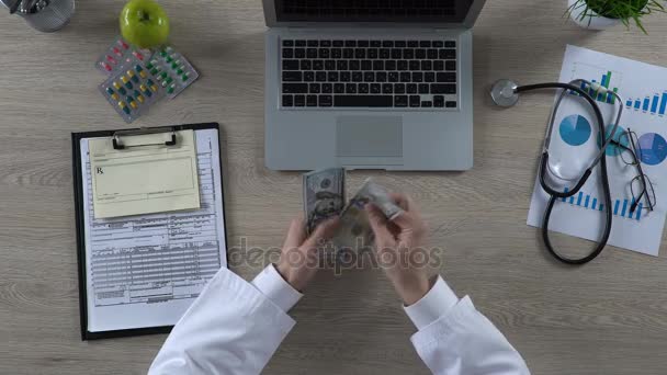 Médico contando billetes de dólar, recompensa por servicios de salud, vista superior — Vídeo de stock