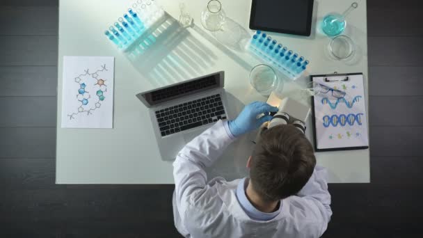 Gli scienziati visualizzano campioni al microscopio e scrivono risultati su laptop in laboratorio — Video Stock