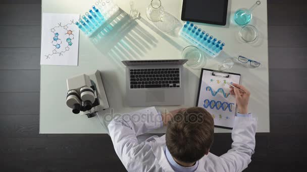 Ιατρική φοιτητής που σπουδάζει εικόνα Dna, καθιστώντας τις σημειώσεις στον φορητό υπολογιστή, γενετική, το top view — Αρχείο Βίντεο
