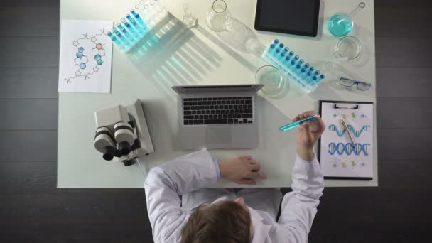 Biologiestudent checkt Flüssigkeit im Reagenzglas und tippt Forschungsergebnisse auf Laptop — Stockvideo