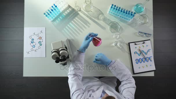 Trabajador de laboratorio neutraliza el color púrpura del líquido en el frasco mediante la adición de reactivo — Vídeo de stock