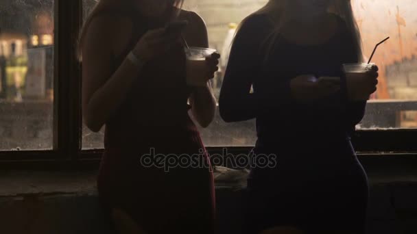 Due ragazze attraenti che controllano i social network, bevono cocktail alla festa — Video Stock