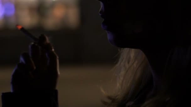 Femme fumant une cigarette dans l'obscurité, inhalant de la fumée toxique, risque de cancer 