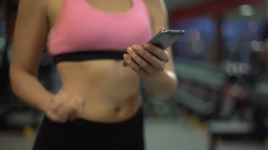 Çekici kız bilgisi üstünde hareket eden telefon içinde jimnastik salonu, Fitness app kullanarak