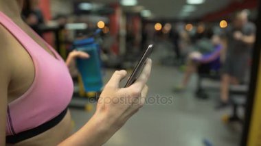 Spor salonunda egzersiz molası verdikten kız cep telefonu, su şişesi elinde kontrol