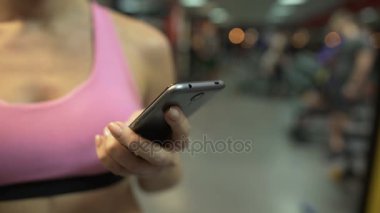 Spor salonunda egzersiz ara sahip cep telefonu sayfalarında kaydırma kadın