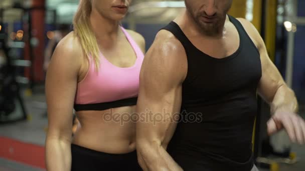 Pareja levantando pesas juntos en el gimnasio, chico mostrando la manera correcta de hacerlo — Vídeo de stock