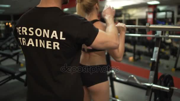 Attraktiv kvinna träna med personlig tränare, lyftande bar i gymmet — Stockvideo