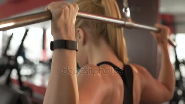 Молодая женщина делает задние подтягивания в спортзале, тренируясь, чтобы иметь тело мечты — стоковое видео