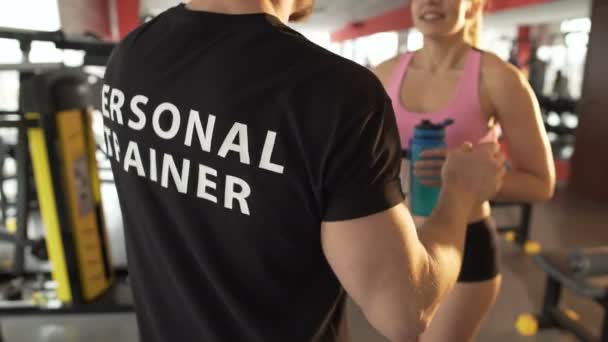 Fitness trenér dělá vlny pohyblivosti před fit girl, flirtování s klientem — Stock video