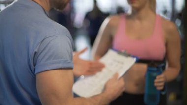 Erkek ve kadın fitness eğitmenleri içinde jimnastik salonu iş planlarını tartışıyor