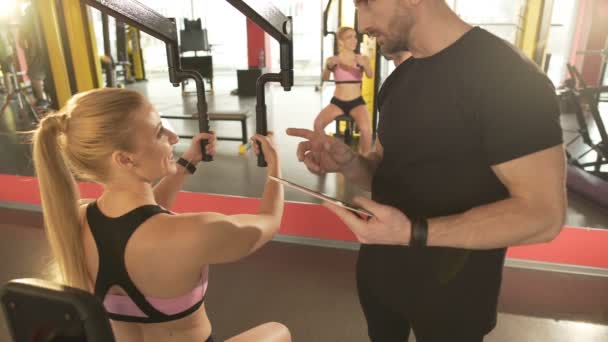 Entrenamiento en el gimnasio, mujer coqueteando abiertamente con su entrenador personal atractivo — Vídeos de Stock