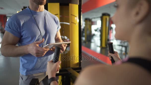 Trainer client vertrouwd te maken met de nieuwste Technogym fitnessapparatuur en bespreken plan van opleiding — Stockvideo