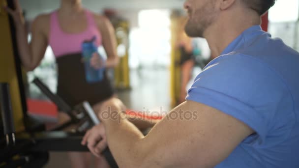 Pareja tomando un descanso en el gimnasio, restaurando el equilibrio hídrico y charlando entre sí — Vídeo de stock