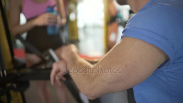 Chico coqueteando con colega femenina en el gimnasio, jugando músculos y sonriendo lindo — Vídeos de Stock