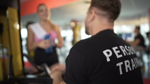 Personal Trainer kommuniziert mit Kundin im Fitnessstudio, schüttelt Hände, Team — Stockvideo
