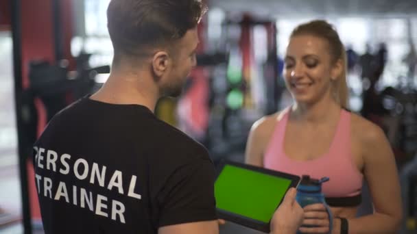 Frau stellt Wasserhaushalt wieder her und diskutiert mit Trainerin im Fitnessstudio — Stockvideo