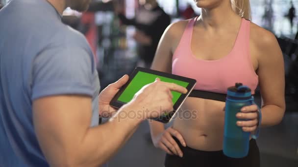 Entrenador explicando el horario de entrenamiento para el cliente femenino, utilizando el ordenador portátil de pantalla verde — Vídeos de Stock