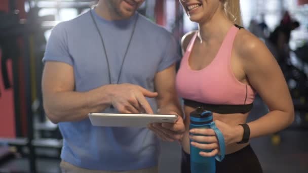 Žena flirtuje s fitness trenérem, mluví o rozvrh cvičení v tělocvičně — Stock video