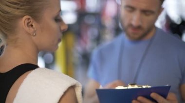 Spor salonunda, onun programı üzerinde çalışan kadın müşteri ile iletişim fitness eğitmeni