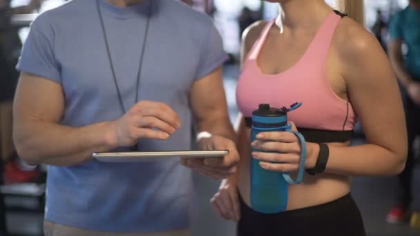 Trainer communiceren met vrouwelijke klant, maken van haar persoonlijke training plan — Stockvideo