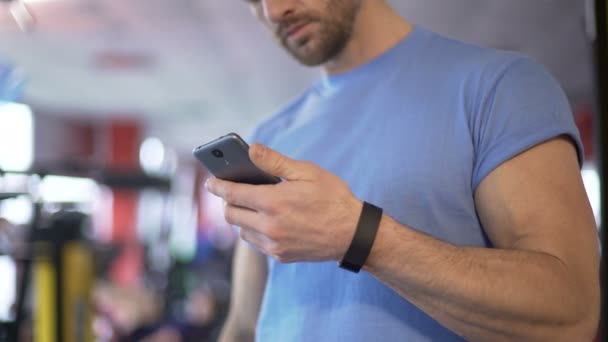 Idrottsman starta program på smartphone synkronisera med fitness armband — Stockvideo