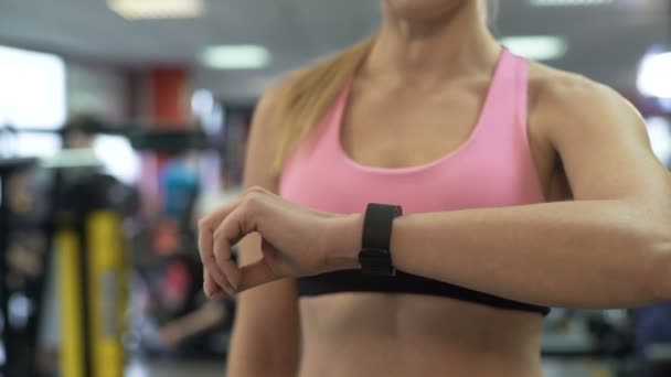 Lady revisando su progreso de entrenamiento usando la pulsera de fitness y la aplicación móvil — Vídeos de Stock