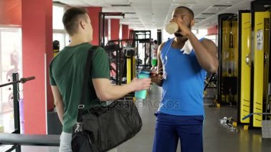 Fitness kulübünde protein kokteyl içme sporcular konuşurken iki atletik erkek