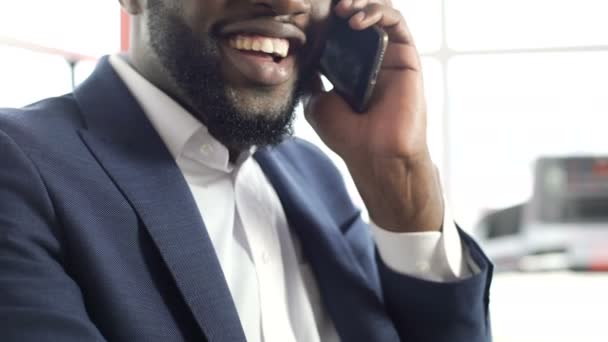 Agradable hombre afroamericano en traje hablando por teléfono celular, haciendo una cita — Vídeos de Stock