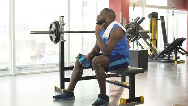 Homme afro-américain fatigué assis sur l'équipement d'entraînement après l'entraînement actif — Video