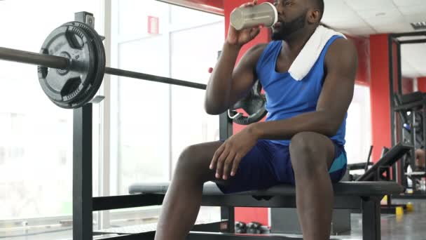 Glückliche afroamerikanische Person, die im Fitnessstudio sitzt und über das Leben, Sport nachdenkt — Stockvideo