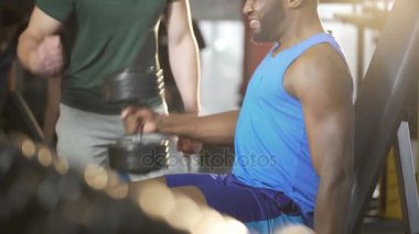 Çak bir beşlik veren spor salonunda, zor egzersiz sırasında genç adam destekleyen arkadaş