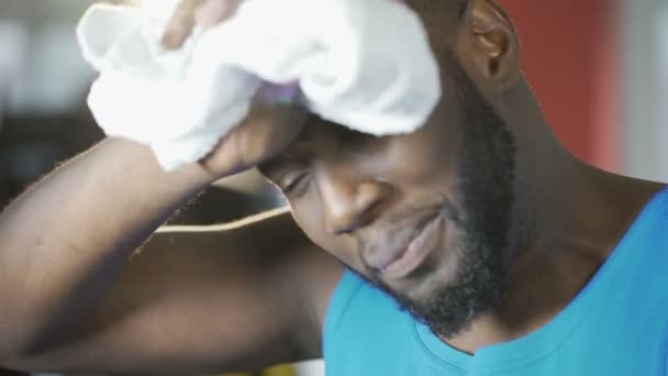 Εργατικοί αρσενικό αθλητής σκουπίζει τον ιδρώτα από το πρόσωπο μετά από εντατική προπόνηση στο γυμναστήριο — Αρχείο Βίντεο