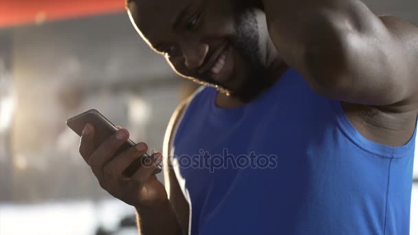 Tímido hombre guapo leyendo mensaje en el teléfono inteligente con sonrisa en la cara, coqueteando — Vídeos de Stock