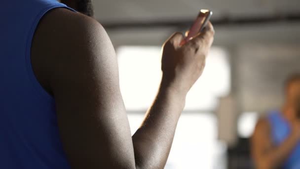 Hombre atlético que utiliza la aplicación de fitness en el teléfono móvil, pantalla táctil de desplazamiento — Vídeos de Stock