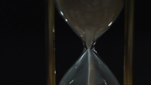 Белый песок вытекает из часового стекла, срок службы истекает и подходит к концу — стоковое видео