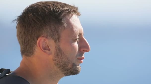 Relajado viajero masculino feliz disfrutando de la brisa del mar y la luz del sol caliente en la playa — Vídeos de Stock