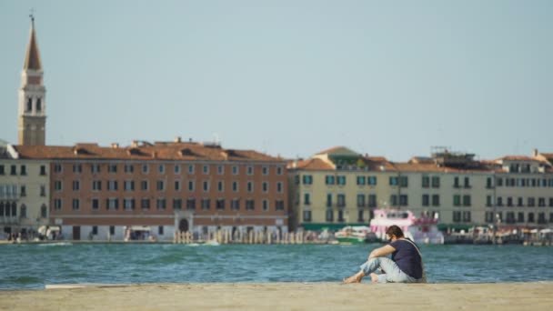 Расслабленная женщина, наслаждающаяся отдыхом и сидящая на пирсе в Венеции, вид на Большой канал — стоковое видео