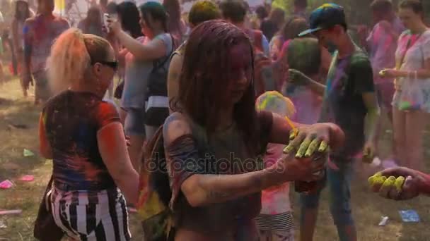 KIEV, UKRAINE - AUGUST 9, 2015: Celebration of Holi Color festival. Girlfriend covered with bright powder trying to treat boyfriend with cocktail — Stock Video